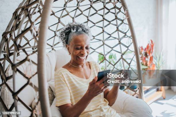 A Senior Woman Using Her Credit Card Holding Her Cell Phone In The Living Room Of The House Stock Photo - Download Image Now