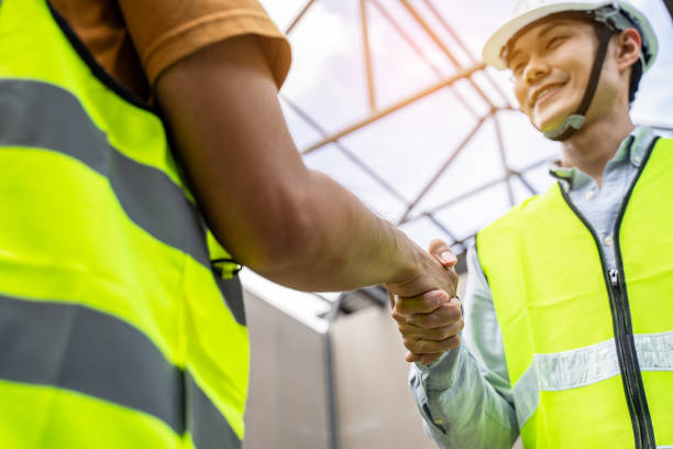 istock Asian structure engineer and worker making handshake on building working site. All people wearing safety hardhat during walking in construction workplace. Business deal, merger and acquisition concept 1289001181