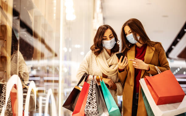 dwie młode przyjaciółki w maskach medycznych podczas zakupów w centrum handlowym - shopping zdjęcia i obrazy z banku zdjęć