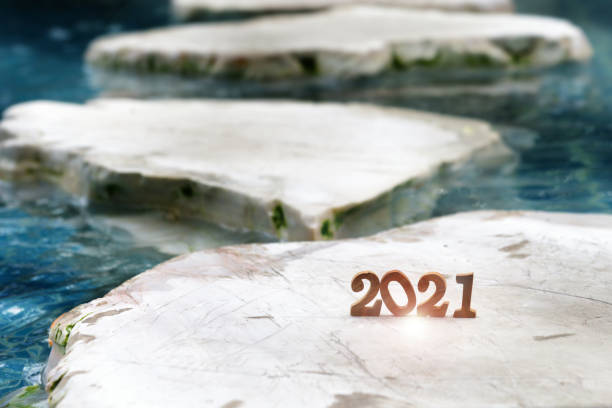 istock Wooden number 2021 on rock marble on pool background 1289002001