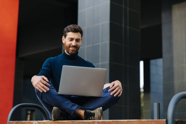istock Stylish man looking at computer screen outdoors 1289004207