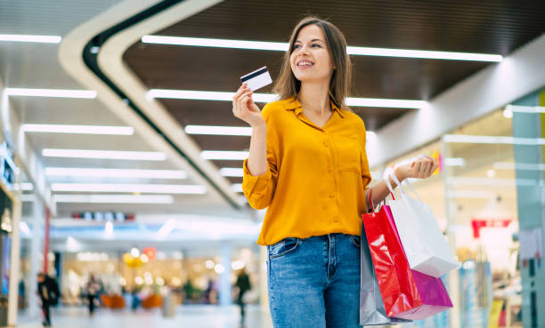 흥분 화려한 미소 젊은 여자는 쇼핑몰에서 신용 카드와 쇼핑 백으로 포즈를 취하고있다 - credit card shopping retail buying 뉴스 사진 이미지