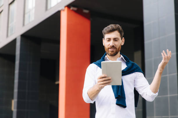 istock Man standing on street and having video call on tablet 1289005573