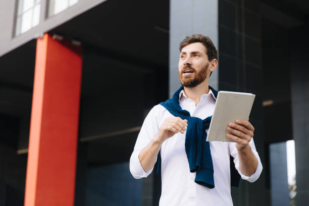 istock Bearded man having online meeting on tablet outdoors 1289006163