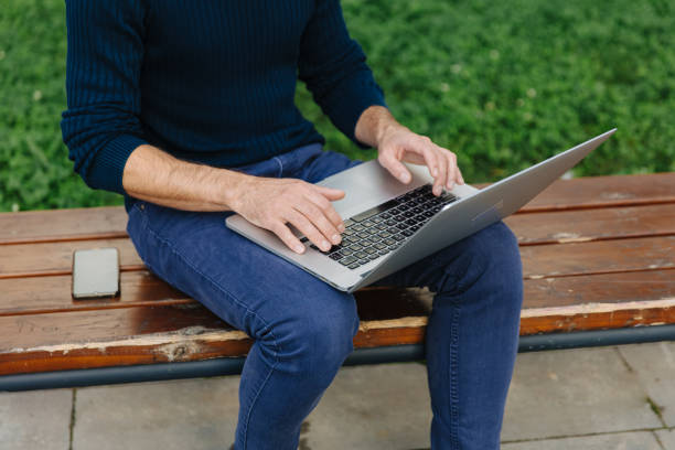 istock Male freelancer sitting bench and working on laptop 1289007416