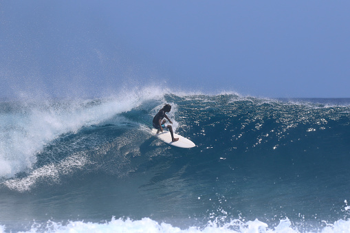 A local Maldivian surfer flies across a breaking wave