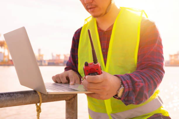 istock An engineer is using a tablet to work, he is at the shipping dock. Use radio communication for notifications and work orders. 1289009638