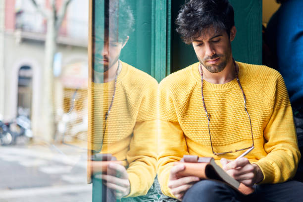 Serious male making notes against window in cafe
