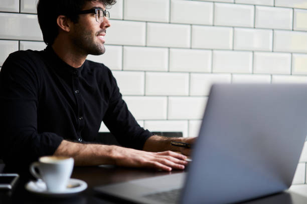 istock Cheerful ethnic man taking notes at laptop in cafe 1289013559