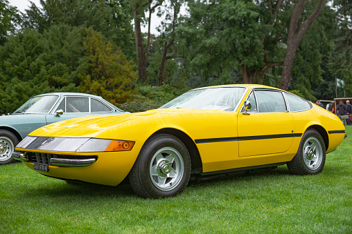 Bright yellow Ferrari 365 GTB/4 Daytona Italian 1970s sports car. The 365 GTB/4 is a two-seat grand tourer produced by Ferrari from 1968 to 1973 and was nicknamed Daytona after Ferrari's 1-2-3 finish in the February 1967 24 Hours of Daytona.  The car is on display during the 2017 Classic Days event at Schloss Dyck. People in the background are looking at the cars.