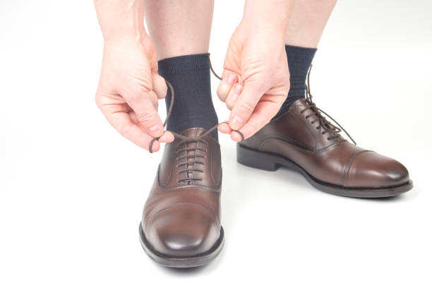 istock Man tying shoelaces on classic brown shoes 1289015395