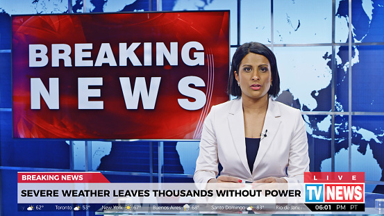Female anchor presenting breaking news about extreme weather causing power outage.