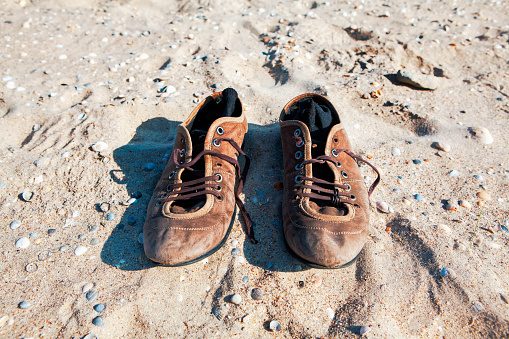 Old leather shoes on the beach . Socks inside shoes