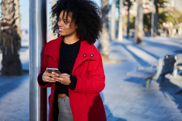 istock Cheerful black woman browsing smartphone in city 1289018354