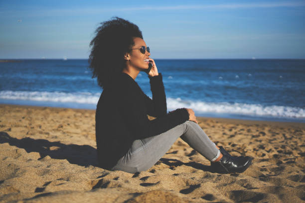 istock Positive black woman having phone call on seashore 1289018357