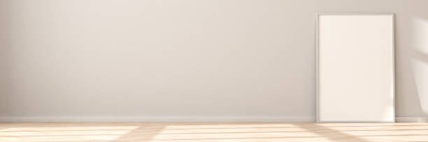 istock Vertical empty Picture Frame on parquet floor leaning against bright wall. Sunlight flooding in from the left. Web banner size with plenty of additional copy space. 1289019741