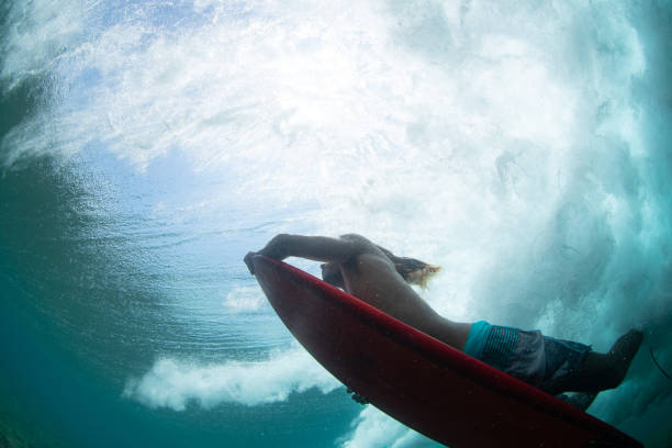 A Maldivian surfer on a red surfboard in a cloud of bubbles