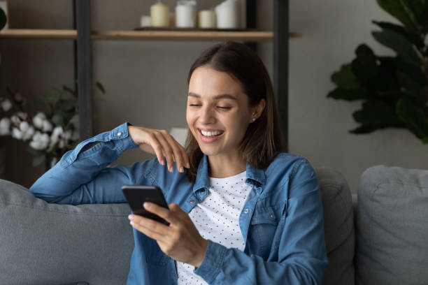 istock Smiling woman use cellphone relaxing at home 1289021239