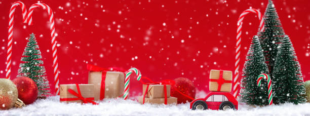 istock Festive composition Christmas red car with a gift box in a pine forest where many different presents on red background. Happy New Year card concept 1289021258