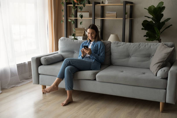 istock Young woman relax on couch using smartphone 1289021278