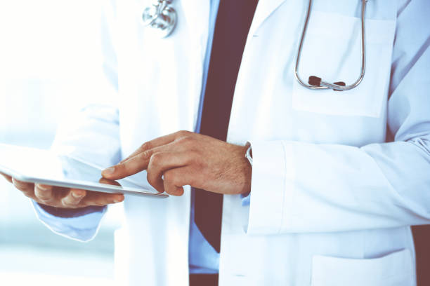istock Doctor man using tablet computer for network research or virtual disease treatment, hands close-up. Perfect medical service in clinic. Modern medicine, medic data and healthcare concepts. Toned picture 1289023539