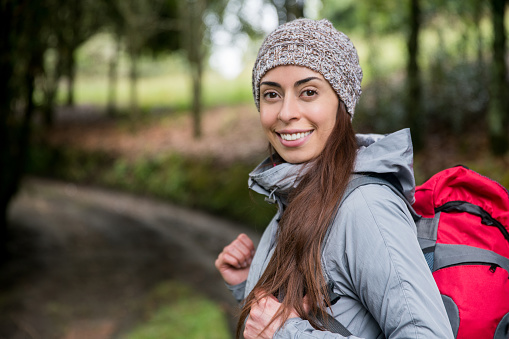Portrait of a happy Latin American woman hiking in the mountains and looking at the camera smiling -outdoor lifestyle concepts
