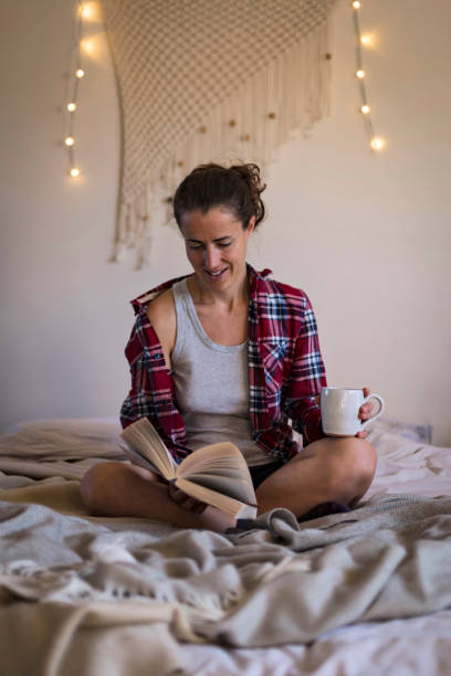 istock Woman relaxing on bed reading book 1289027025