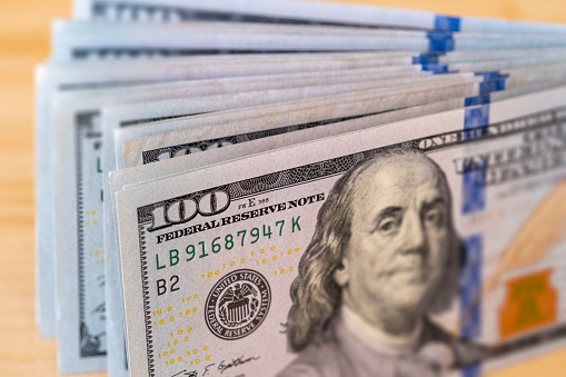 Macro shooting of stack of American 100 dollar bill on wooden table. Image can be used all issues about American economy and financial situations.