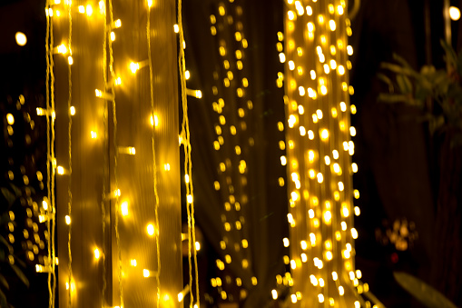 Blurred sparks from fire in front of black backgound. Christmas and New Year holidays concept.  Defocused garland lights, Bokeh effect.