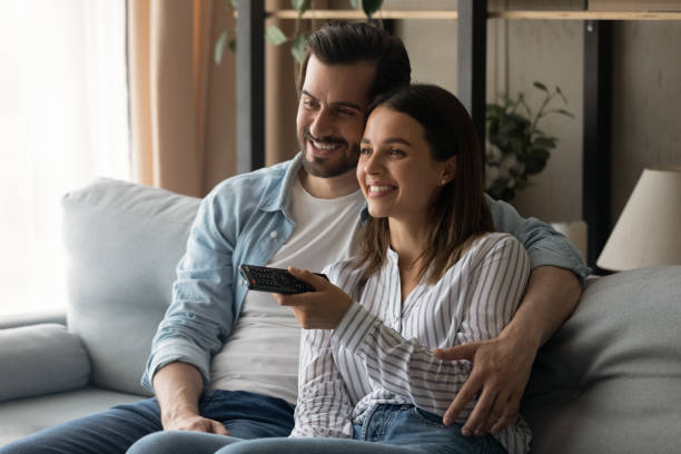 istock Smiling young couple relax on sofa watching TV 1289027500