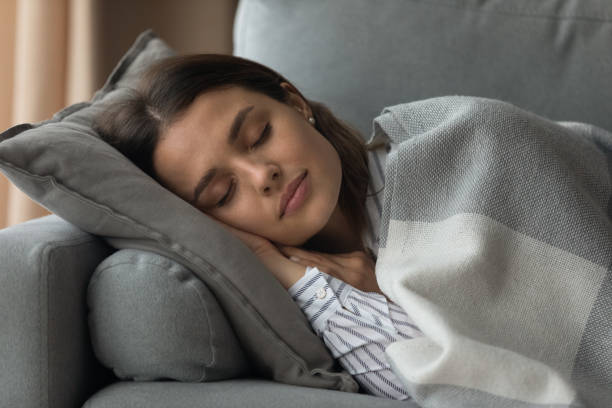 istock Tired young woman relax on couch sleeping 1289027513