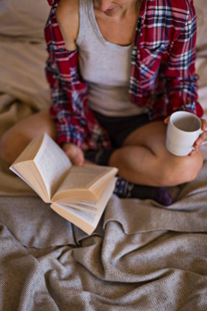 istock Woman reading book on bed in pyjamas 1289029971
