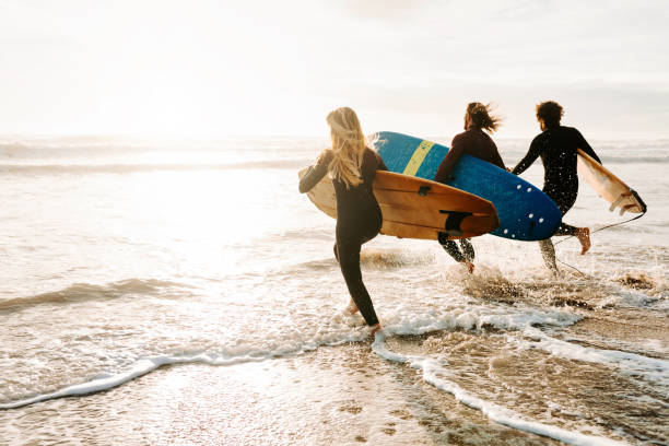 surfer à la plage - horizontal men women surfboard photos et images de collection