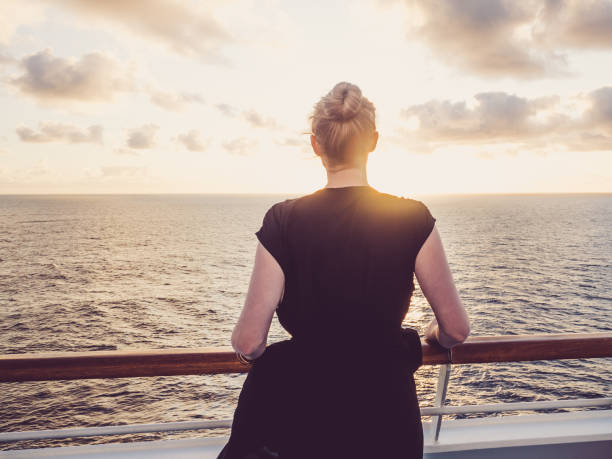 istock Woman Looking at Sunset from Deck of Cruise Ship 1289031712