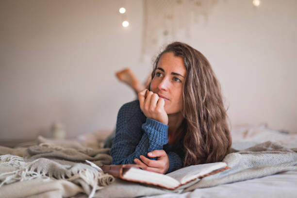 istock Woman lying on her bed thinking about what to write in her journal 1289032314