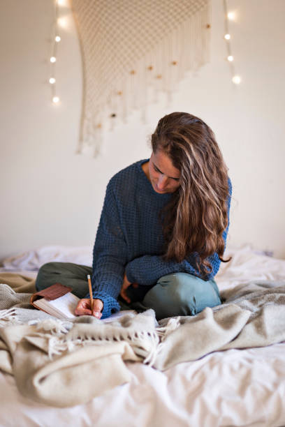 istock Woman on bed writing in her journal 1289032333
