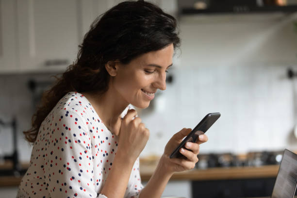istock Smiling woman use modern smartphone at home 1289033391