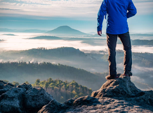 Man watch thick mist in valley from rocky view point