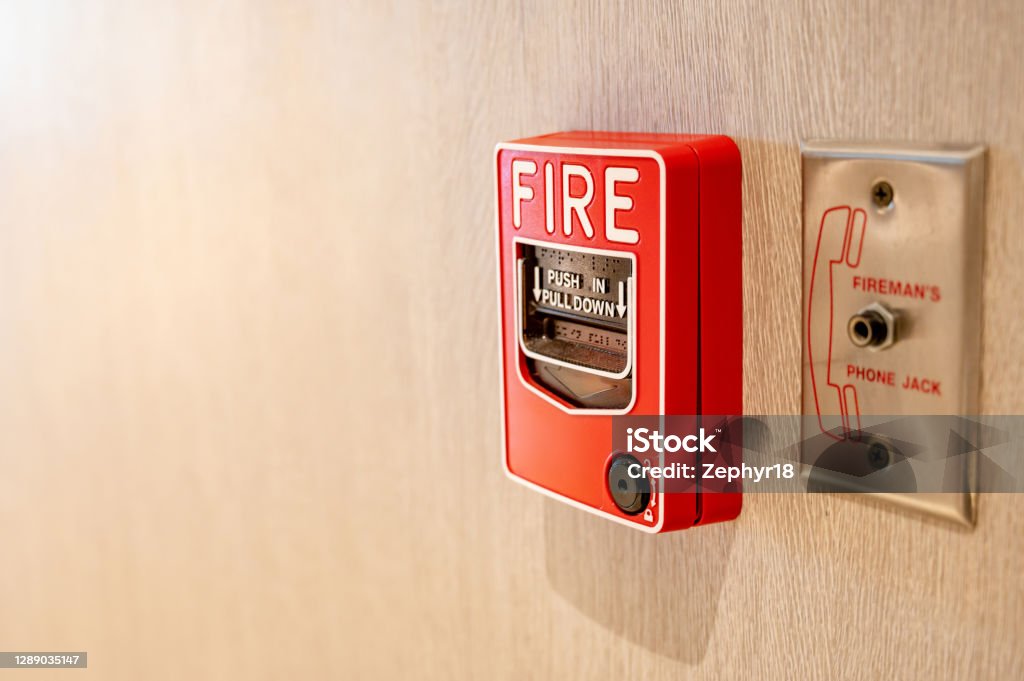 Fire alarm switch and phone jack on wooden wall Red fire alarm switch and phone jack for fireman on wooden wall in office building. Industrial fire warning system equipment for emergency. Fire Alarm Stock Photo