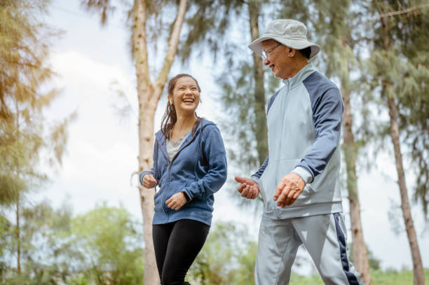 한 여성과 할아버지가 공원에서 길거리에서 조깅을 하고 있습니다. 할아버지는 과거의 삶의 경험에 대해 이야기합니다. 건강하고 라이프 스타일 개념. - running jogging asian ethnicity women 뉴스 사진 이미지