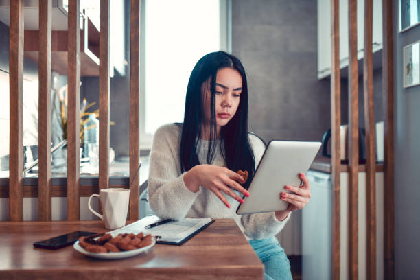 istock Cute Asian Female Working On Digital Tablet While Eating Breakfast 1289036824