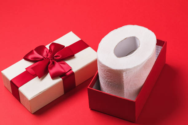 istock Roll of toilet paper in a gift box on a red background 1289037103