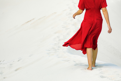 Vista parcial trasera de la hembra caminando descalza en arenas blancas duna photo