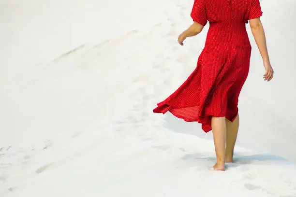 Photo of Rear partial view of female walking barefoot in white sands dune