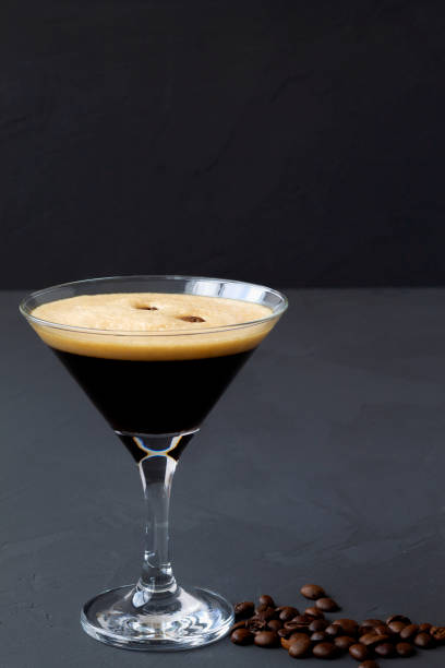istock Espresso Martini cocktails garnished with coffee beans on table. Martini glass on a black background. vertical. alcohol drinks 1289038757