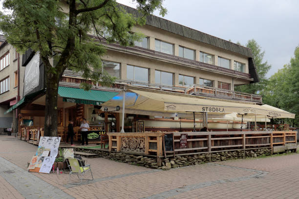 Orbis building on Krupowki street in city of Zakopane in Poland Zakopane, Poland - September 20, 2016: People are walking along the street Krupowki that is the most visited shopping zone and pedestrian promenade in the town. The city of Zakopane is located at the foot of the Tatra Mountains in southern Poland. The unquestionable attraction of the city is the diversity of traditional wooden architecture, which has its own style characteristic for this region. Modern architecture in this city very often also refers to the architectural traditions of this local style. Due to its location, the area is visited by many tourists at any time of the year in order to enjoy the marvelous nature and mountain landscapes or to take advantage of sports opportunities. The city is one of the most visited cities in Poland, both by domestic and foreign guests. Due to the variety of winter sports opportunities, this city is commonly called the winter capital of Poland. orbis stock pictures, royalty-free photos & images