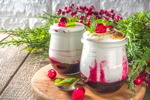 Cranberry layered Dessert breakfast in small jars for Christmas morning. Homemade baked Cranberry meringue dessert, with fresh cranberries and mint, copy space