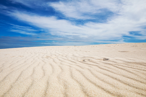 South African white sands beach under a partly cloudy sky and a few footprints in the sand visible.