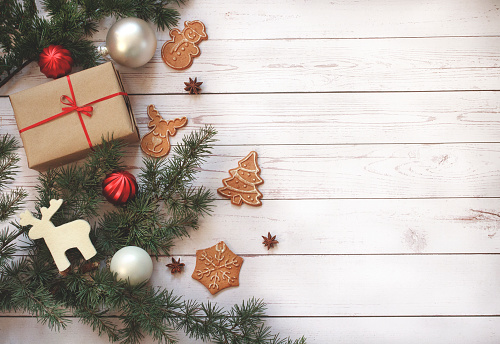 Christmas frame of gingerbread cookies, Christmas present, New Year's balls and pine branches on wooden background. Copy space