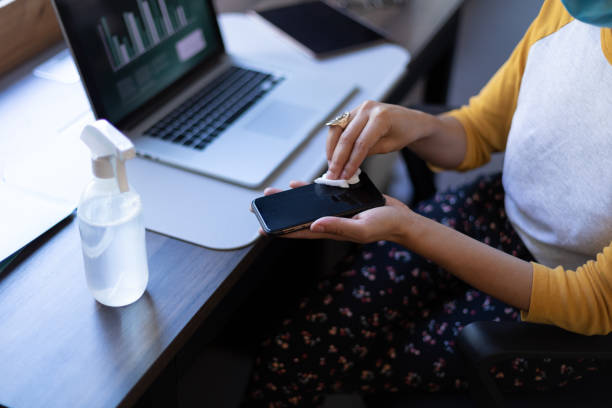 istock Mixed race woman disinfecting her smartphone in an office 1289044329